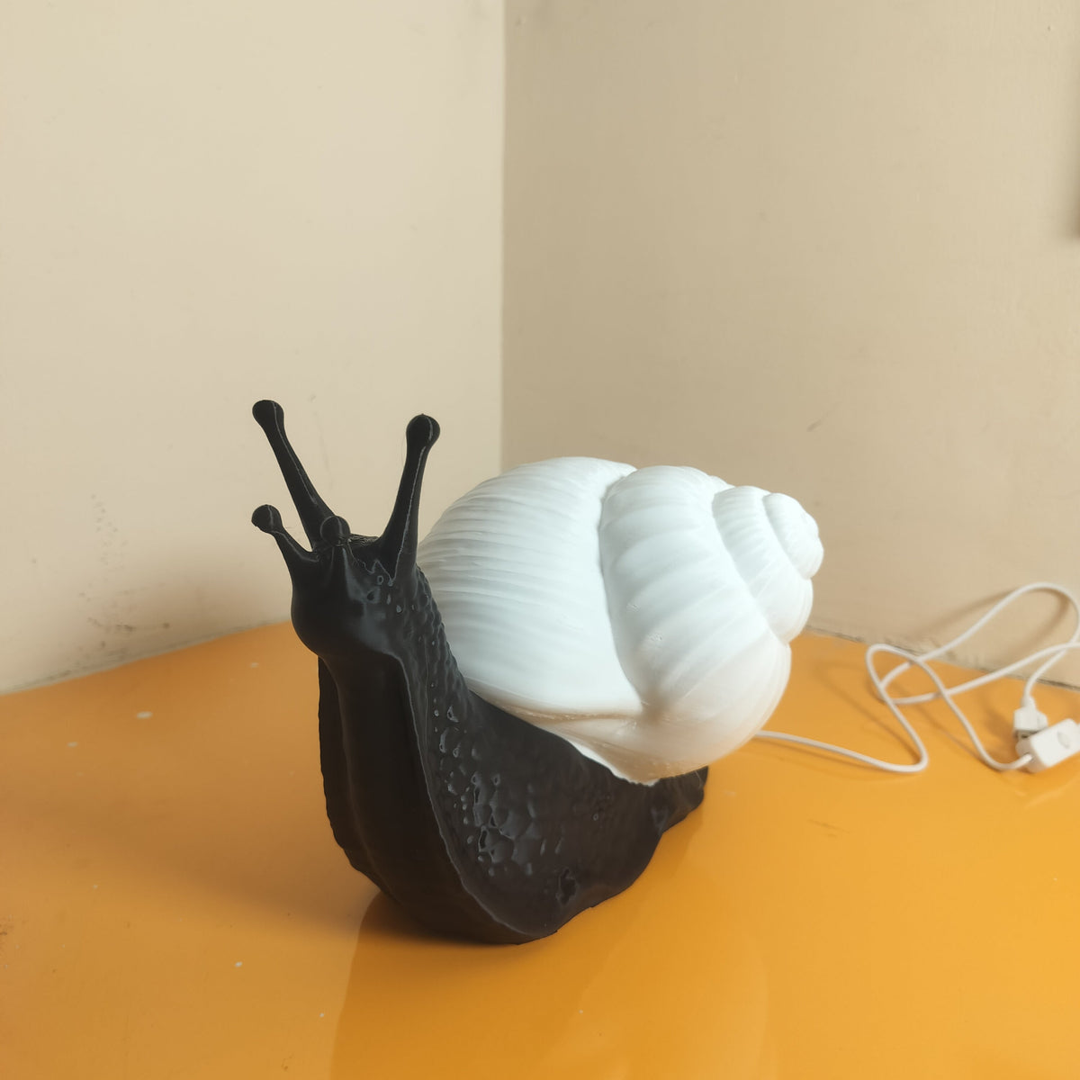 A novelty snail-shaped lamp with a textured black body and a large white spiral shell